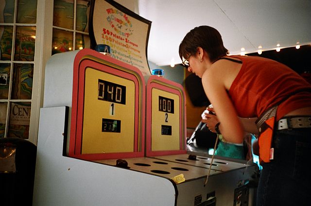 Woman playing whack-a-mole arcade cabinet game.