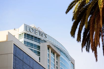 An image of a Loews hotel backdrop with a palm tree peeking in to the corner.