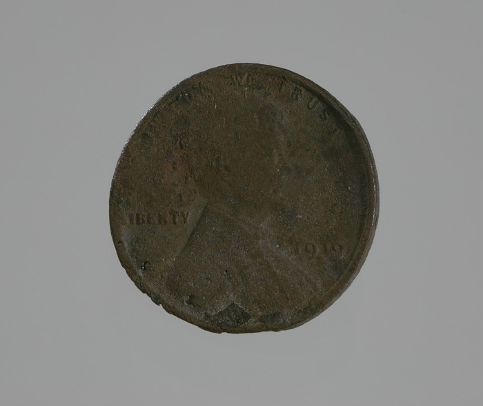 A charred, bent, beat out of shape penny.