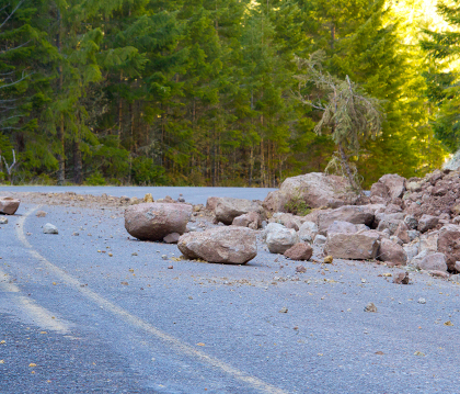 Rocks from a rock-slide covering a canyon road.