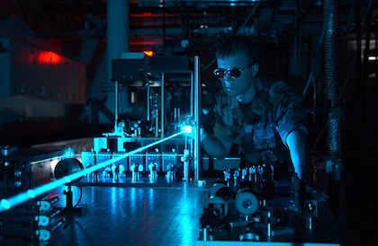 An image of a physicist operating a blue laser with safety goggles in a lab