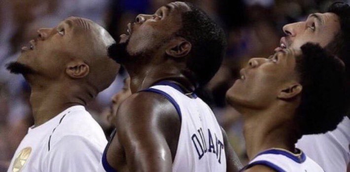 A picture of four basketball players all looking up.