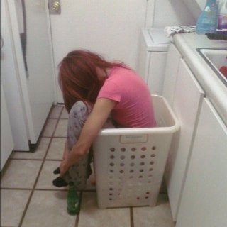 An image of a woman asleep sitting up in a laundry basket.